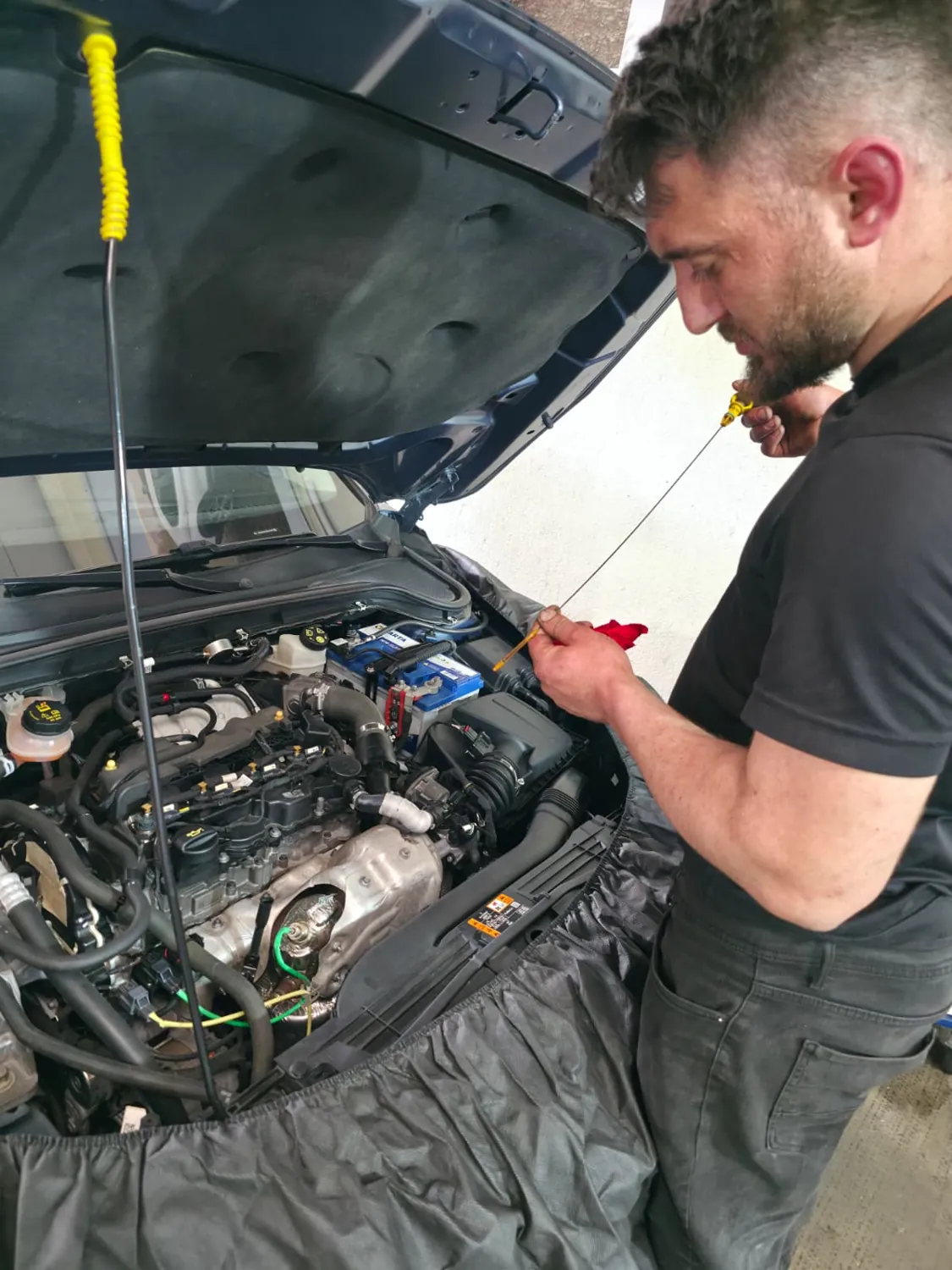 Teknisyen yağ çubuğuyla motor yağı seviyesini kontrol ediyor